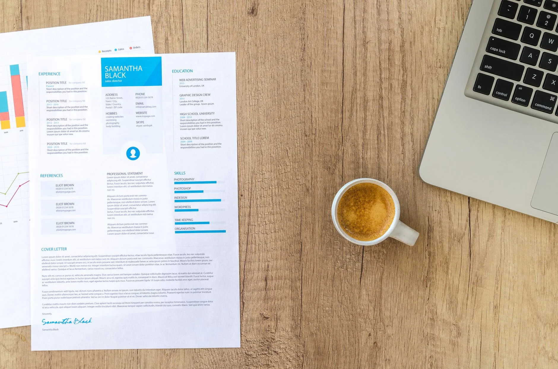Top view of a wooden desk with a printed résumé, a cup of coffee and a laptop.