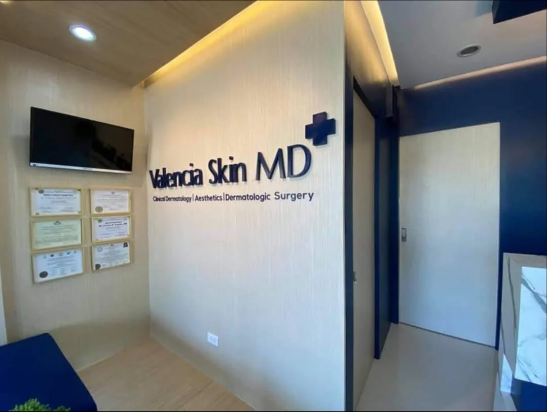 Reception wall of Valencia Skin MD in Quezon City, with the clinic's navy sign and framed medical certificates