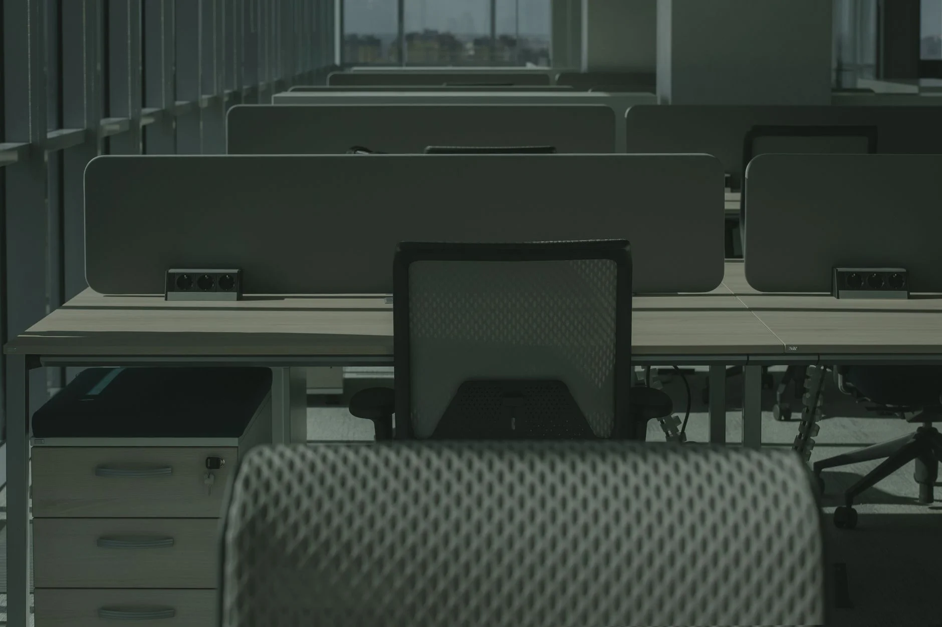 A sleek modern office with multiple desks and chairs, showcasing an empty and orderly workspace.