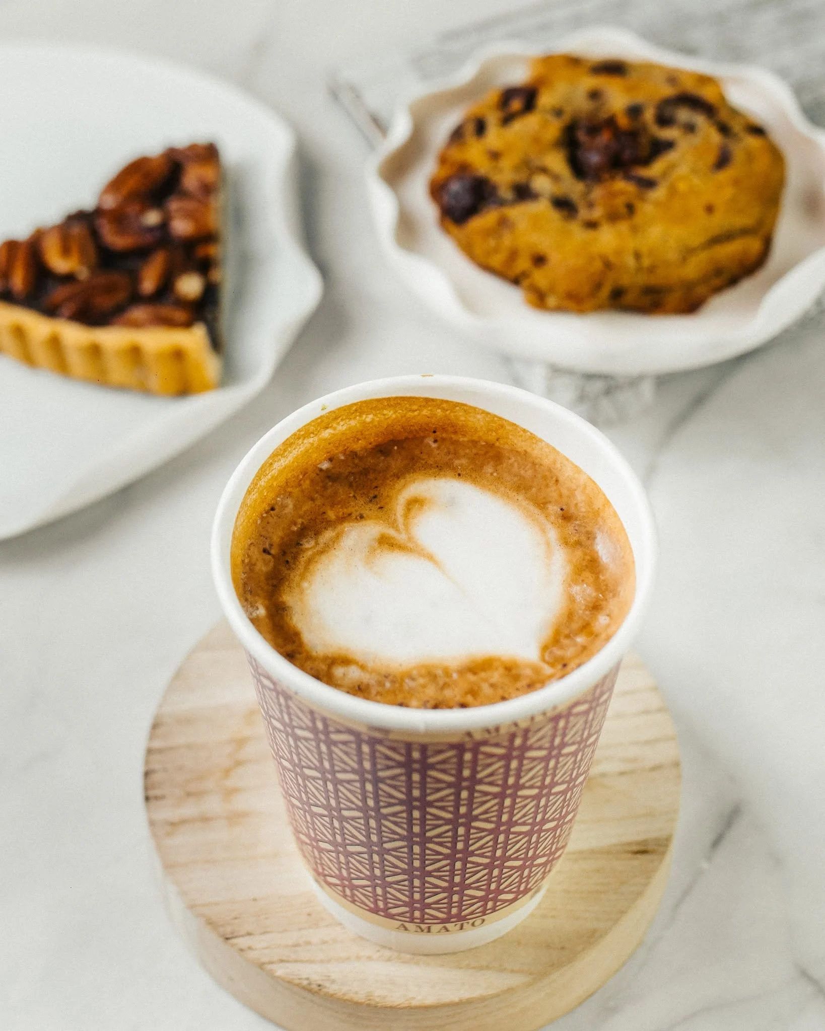 Hot latte with heart art alongside pastries