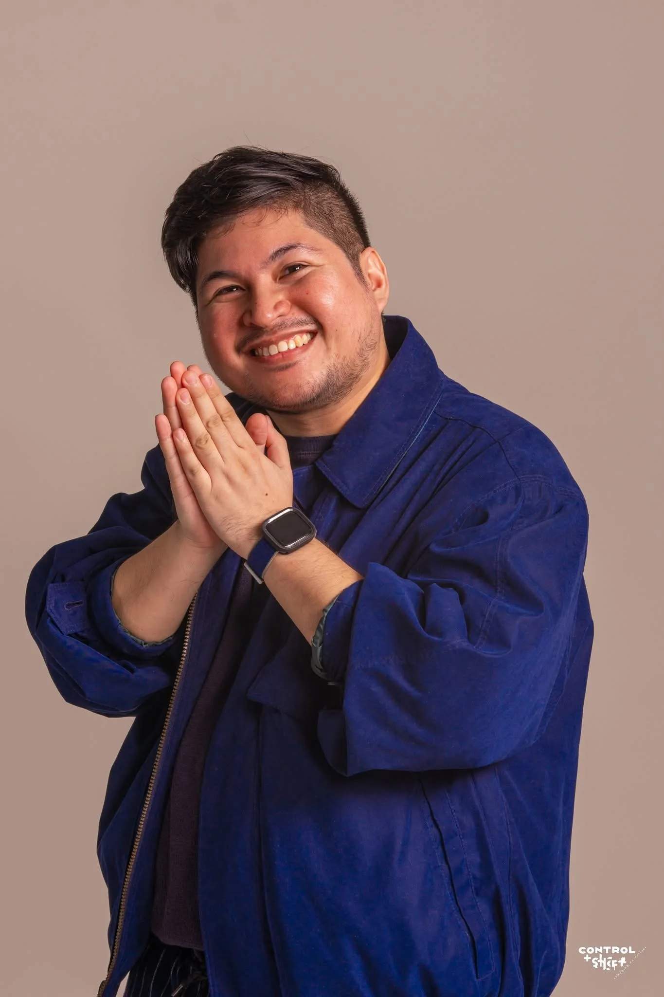 Smiling artist in a blue jacket, hands together